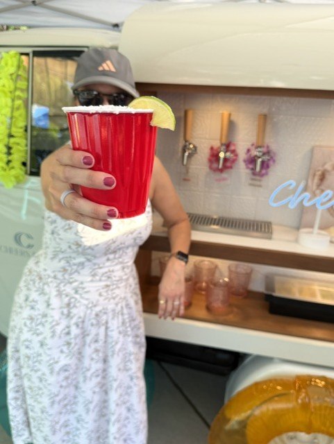 Guest with margarita at the Cheers bar trailer